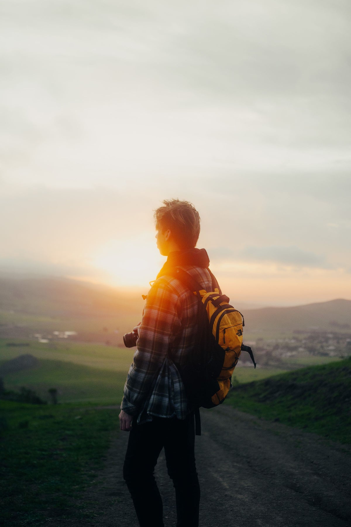 Hiker with backpack watching sunrise over the mountains